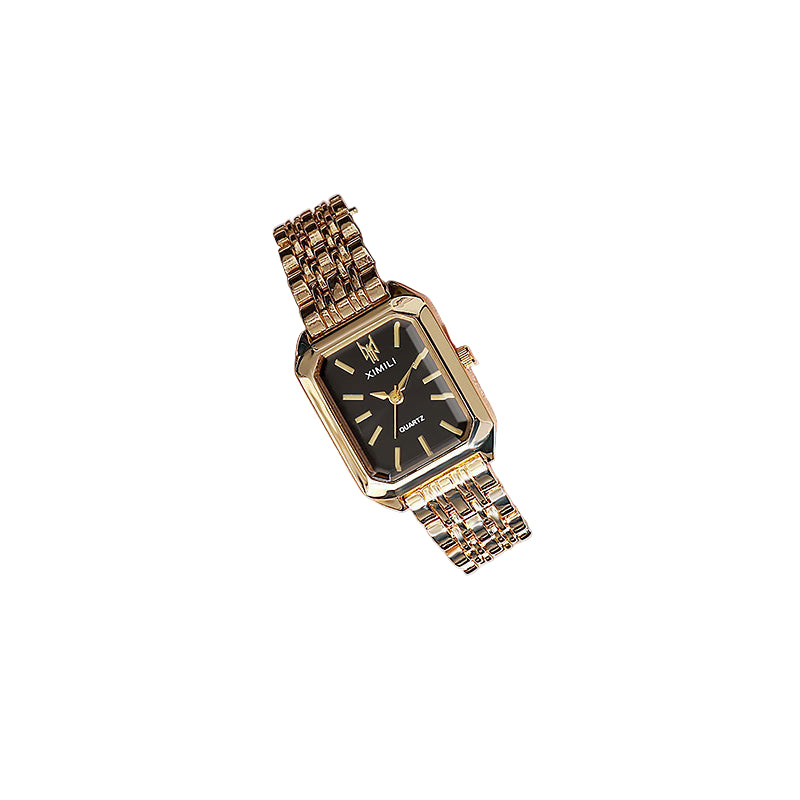 Gold wristwatch with a black face on a person's wrist, wearing a light-colored outfit.