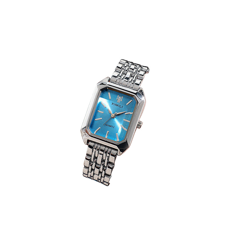 Silver watch with blue face on a wrist, blurred background