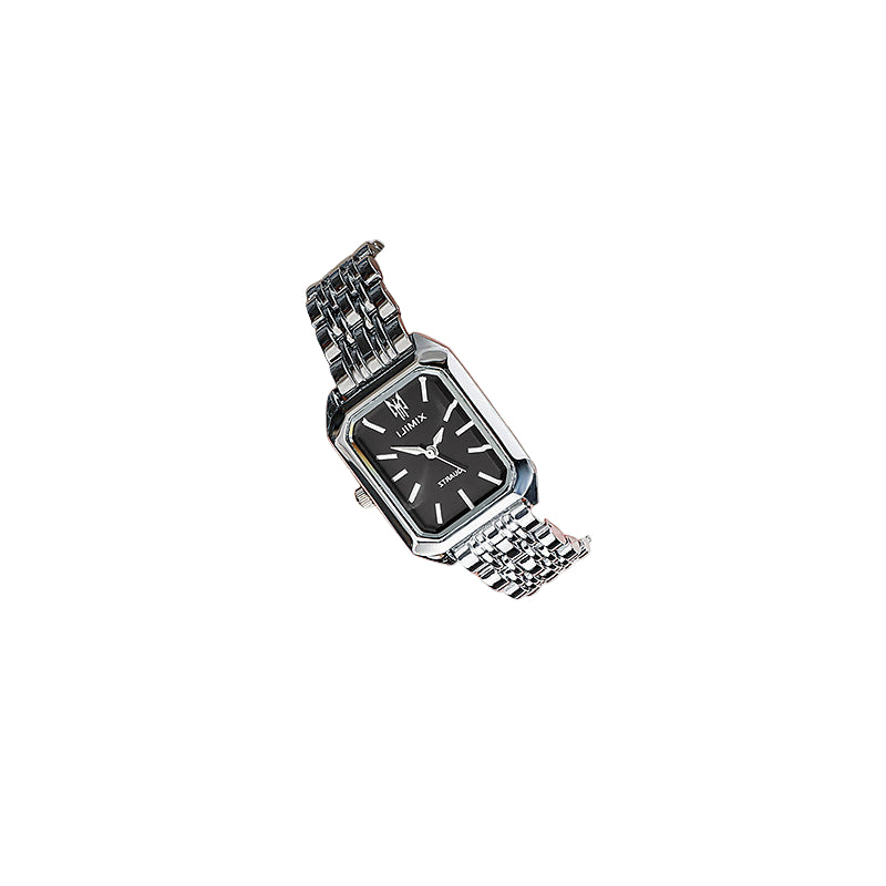 Silver wristwatch with a black face on a person's wrist, wearing a light-colored outfit.