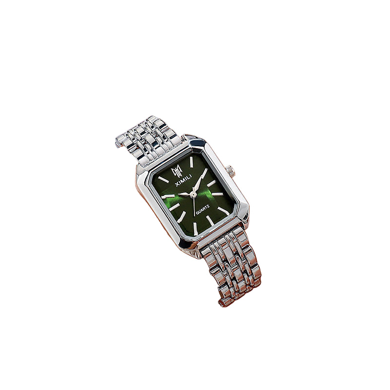 Silver watch with a green face on a wrist against a neutral background