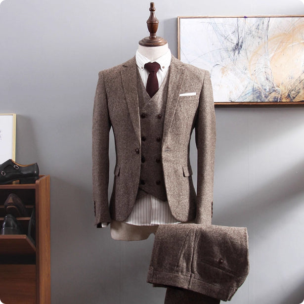 Brown suit on a mannequin against a gray wall with abstract art.